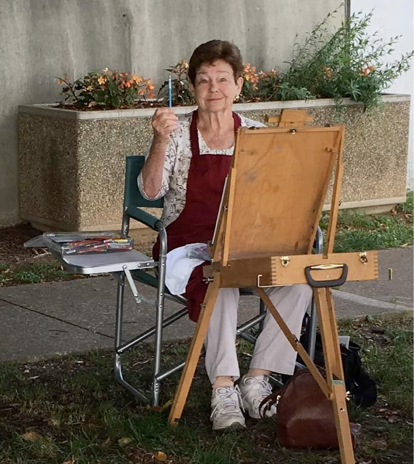 photograph of woman painting outdoors looking at the viewer